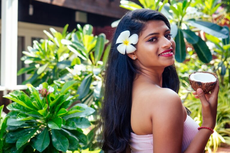 Home-Remedies-for-Hair-Care-mend-Zone, indian woman applying coconut oil dark brunette long hair in a hand on green summer park nature tropical