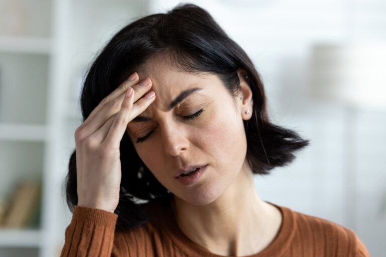 Young woman suffering from a headache, holding her forehead in discomfort.